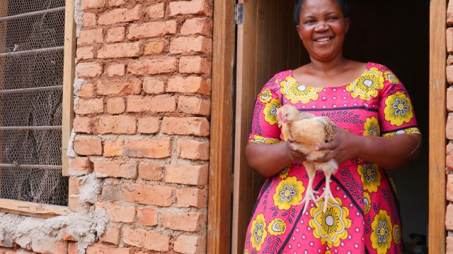 African woman smiling and holding a chicken